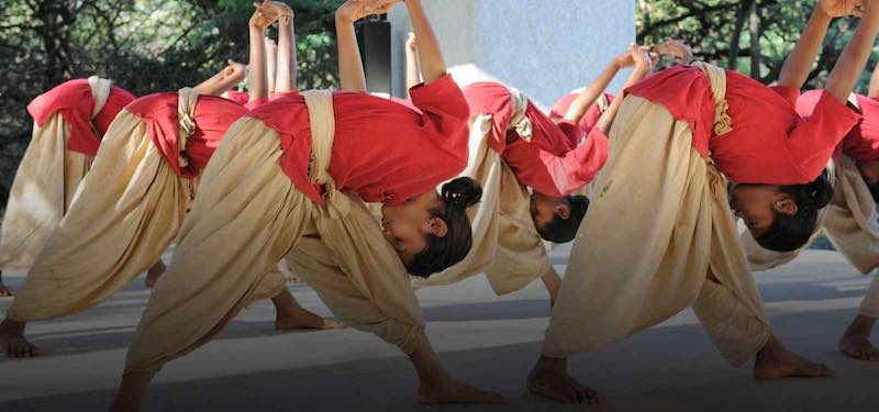 Children practicing dynamic Angamardana yoga poses